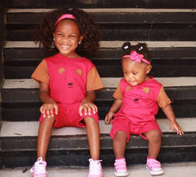 Two toddler sisters in pink and brown strip free romper sitting on stairs 