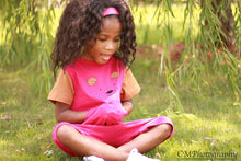 Toddler girl in pink and brown strip free romper sitting on grass