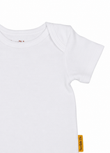 A close-up of a white short-sleeve baby bodysuit or t-shirt, showing the shoulder seam and a small orange brand tag on the sleeve.