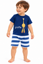 A toddler boy wearing a two-piece pajama set consisting of a navy blue t-shirt with a yellow giraffe graphic and the word 'giraffe' in white, paired with blue and white horizontally striped shorts, standing against a plain white background.