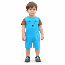 A toddler standing against a plain white background wearing a bright blue short-sleeve romper-style outfit with brown sleeves, a bear face graphic on the chest, and matching blue shorts.